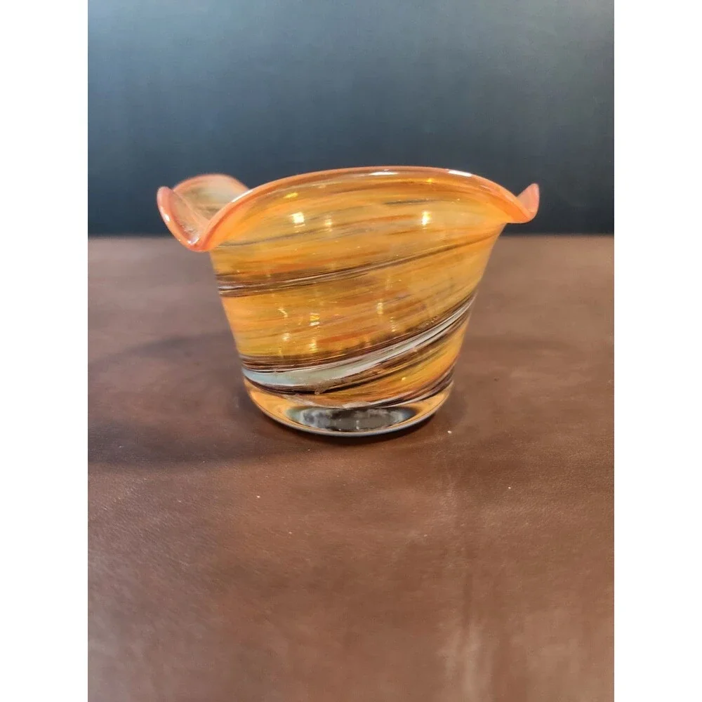 hand-blown art glass bowl features a vibrant orange and amber swirl pattern with